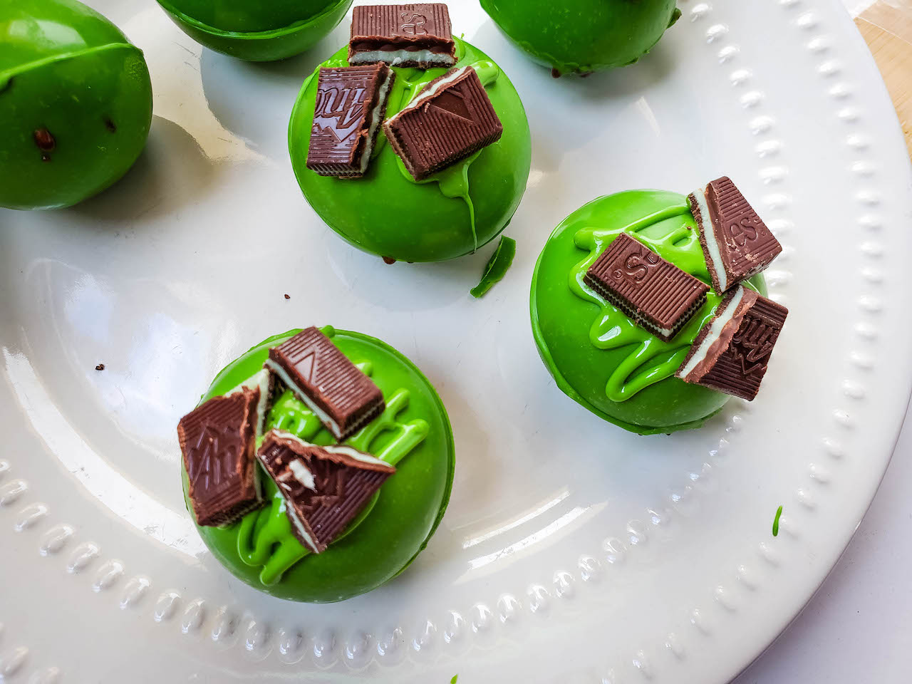 hot chocolate bombs on a white plate topped with Andes mint candies