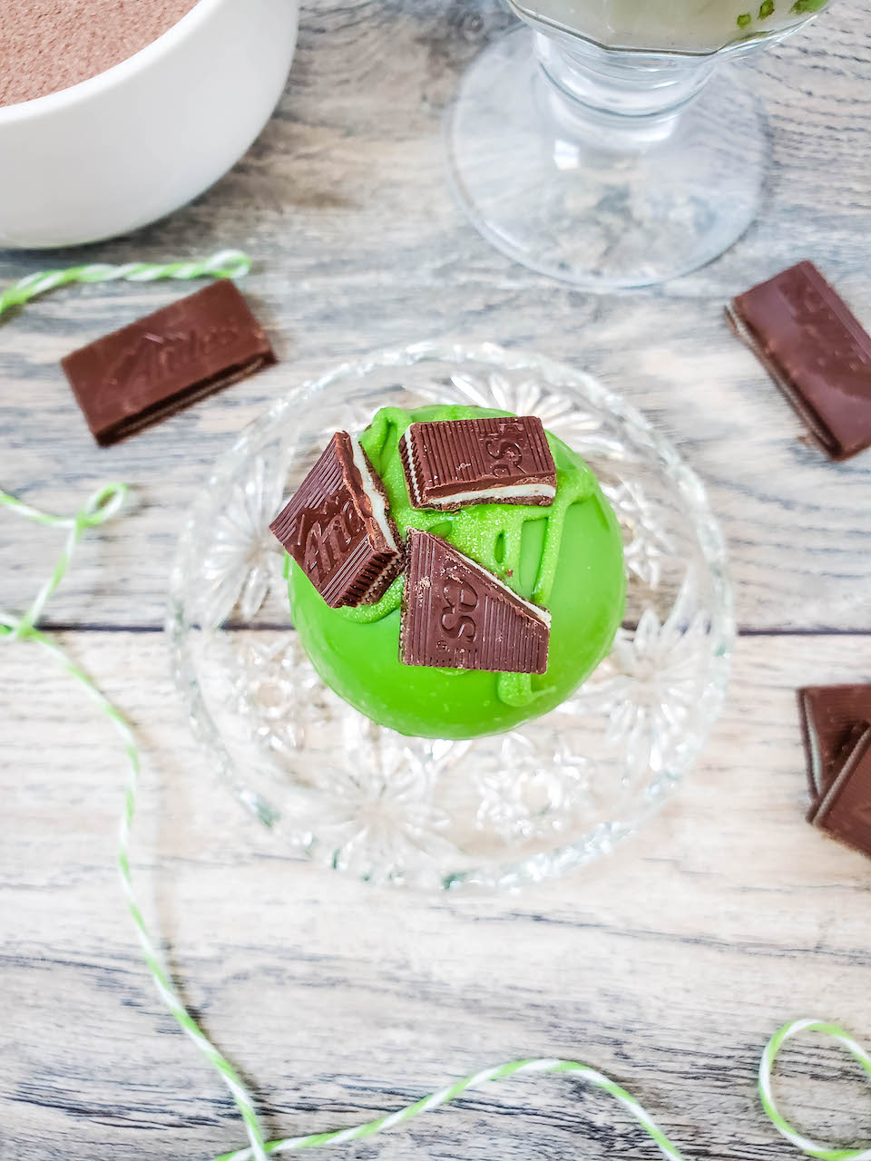 one andes mint hot chocolate bomb sitting on a glass plate with full candies around it