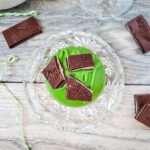 one andes mint hot chocolate bomb sitting on a glass plate surrounded by Andes mint candies