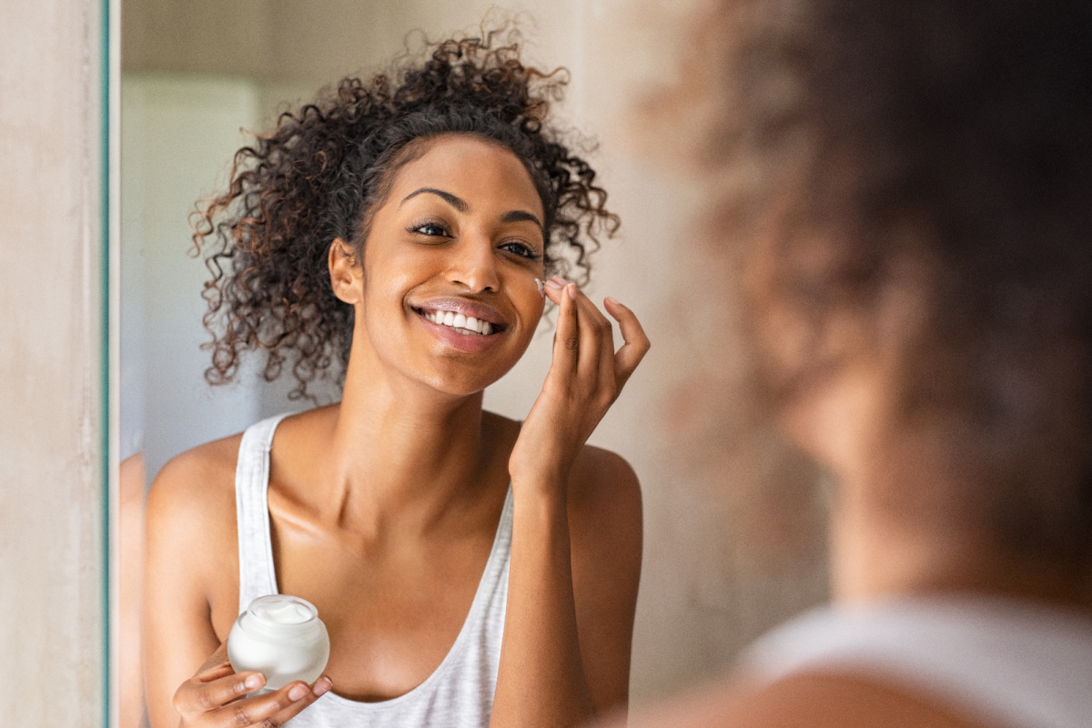 Black woman applying moisturizer