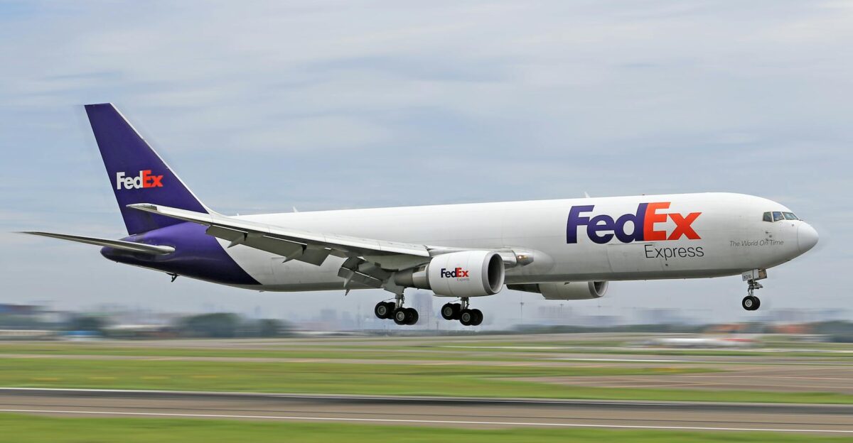 FedEx cargo airplane on the runway during takeoff at a busy airport