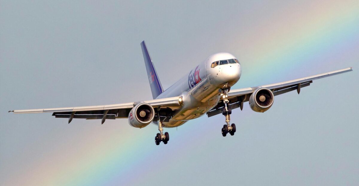 A cargo airplane in flight with a vivid rainbow in the background showcasing a unique aerial view