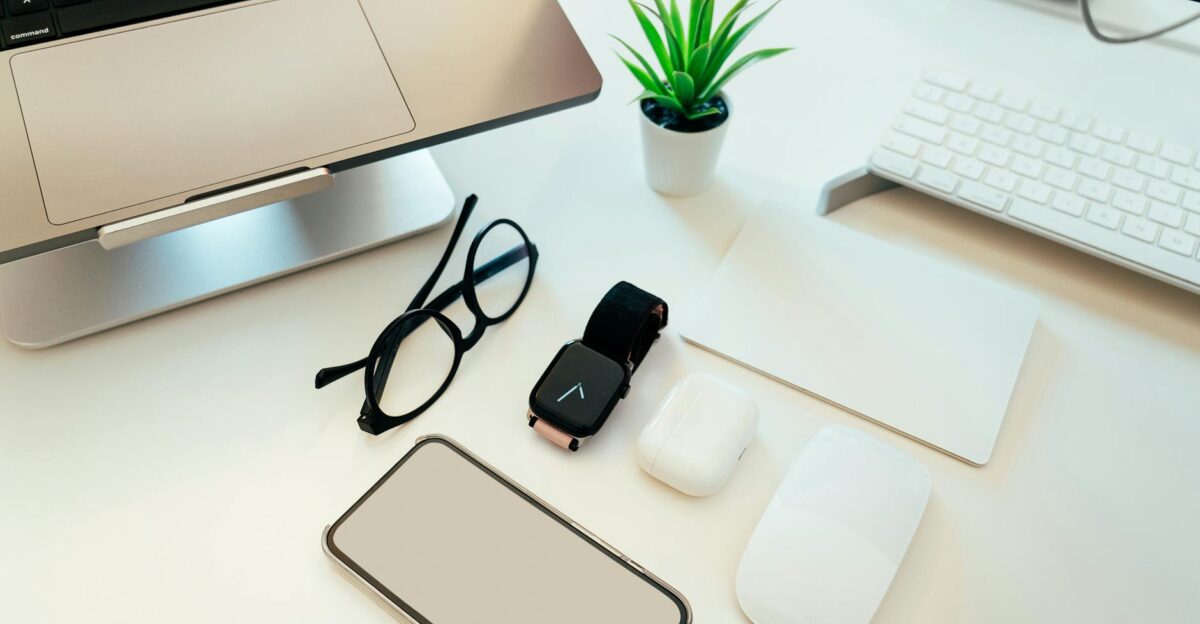 Overhead view of a sleek workspace with a laptop smartphone smartwatch and tech accessories