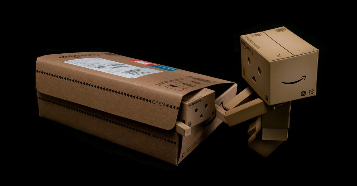 Whimsical cardboard robot figure emerging from a shipping box on a black background