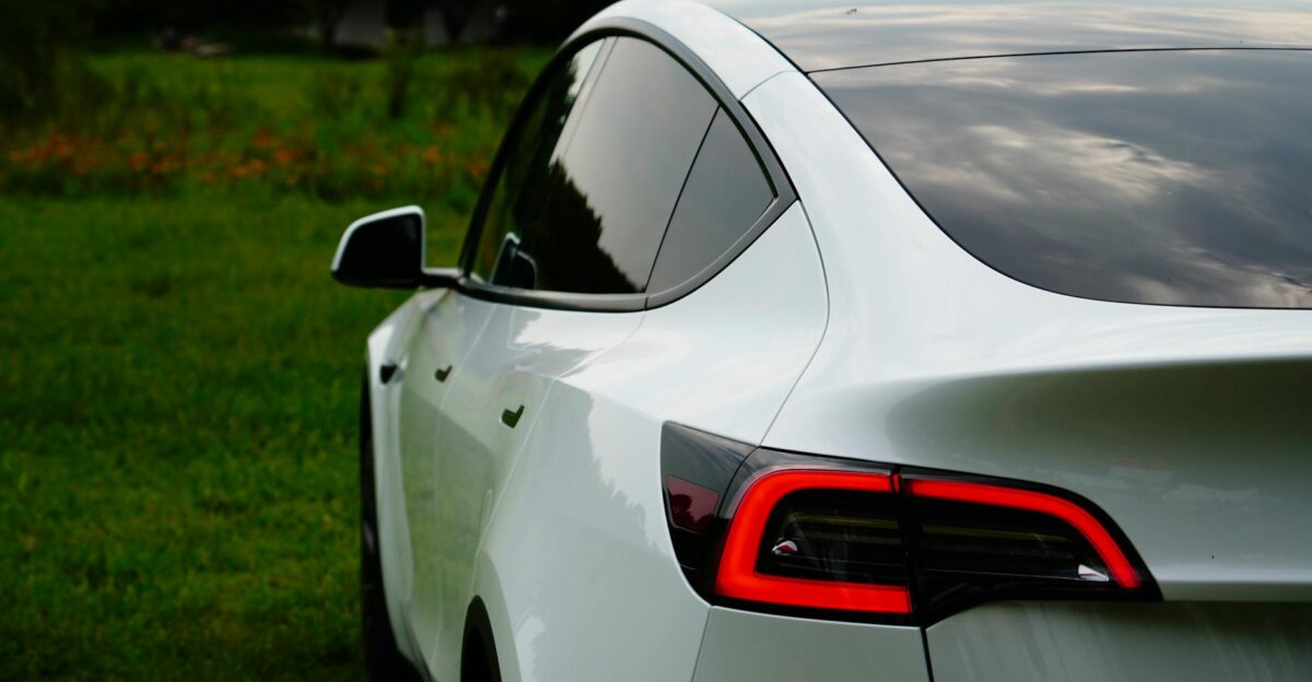 A white Tesla Model Y parked in a lush green outdoor setting highlighting its sleek design