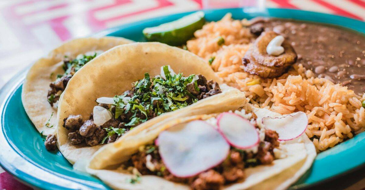 Close-up of delicious Mexican tacos with beans and rice, vibrant and tasty meal.