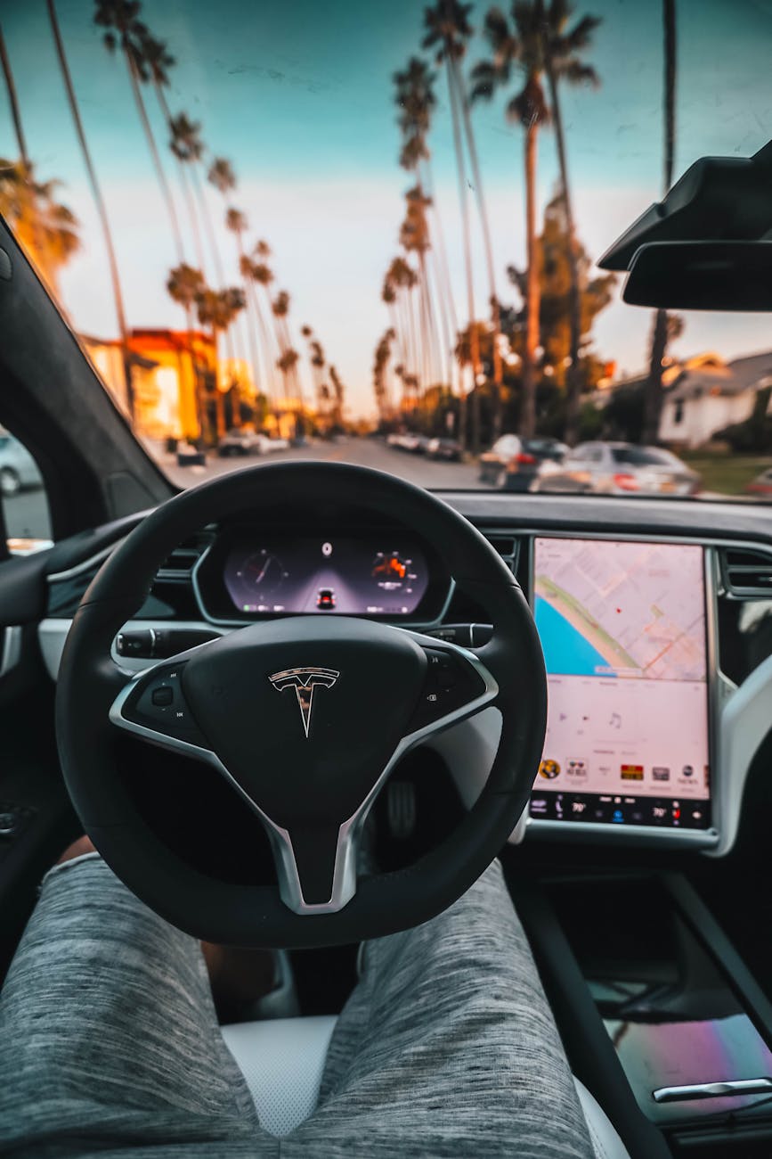 Interior view of a Tesla Model X steering through palm-lined streets of Santa Monica at twilight