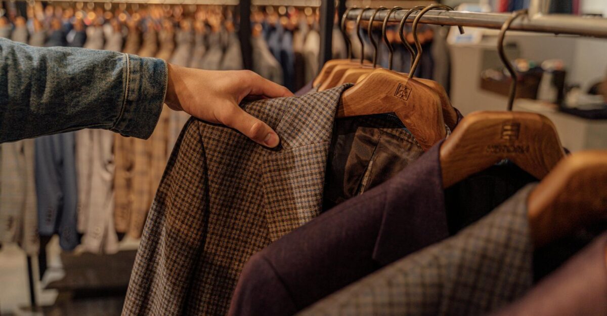 Close-up of a hand selecting men s blazers in a fashion store highlighting trendy styles