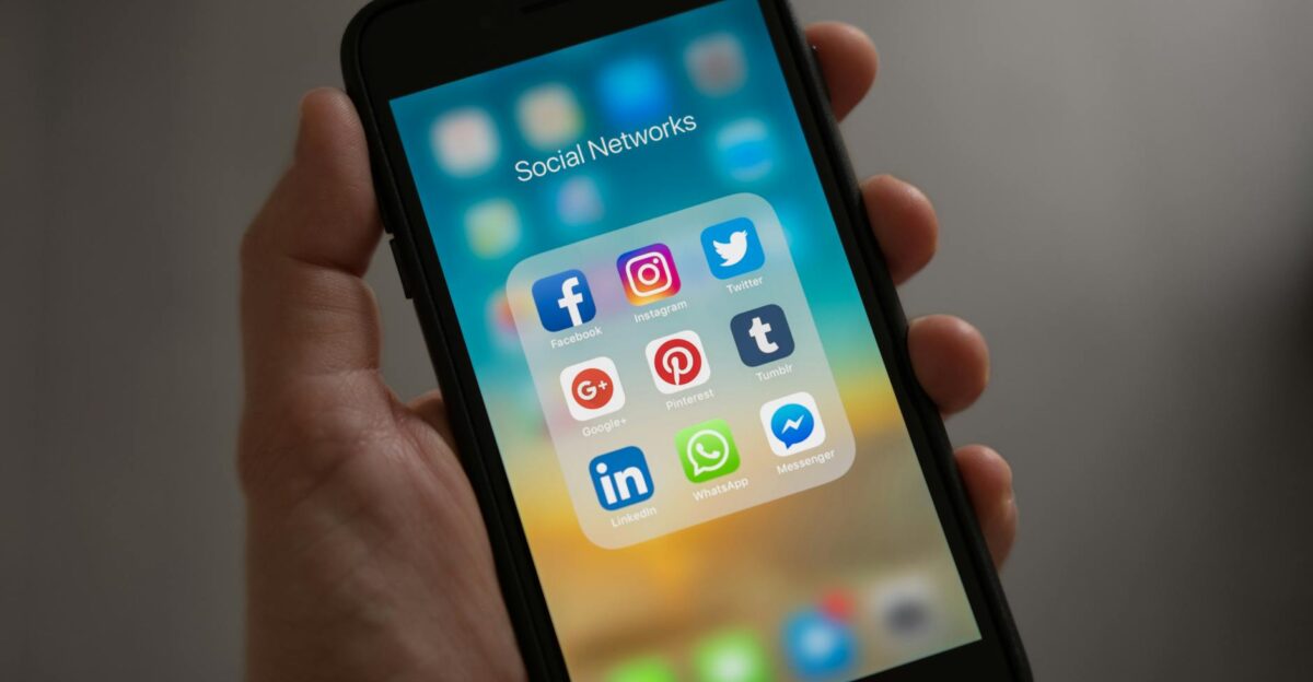 A smartphone displaying various social media icons held in a hand, showcasing modern communication apps.