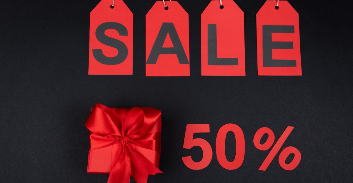 Red gift box next to sale tags and 50 sign on black background ideal for promotions