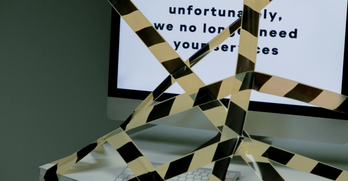 A computer screen taped and displaying a termination message symbolizing unemployment