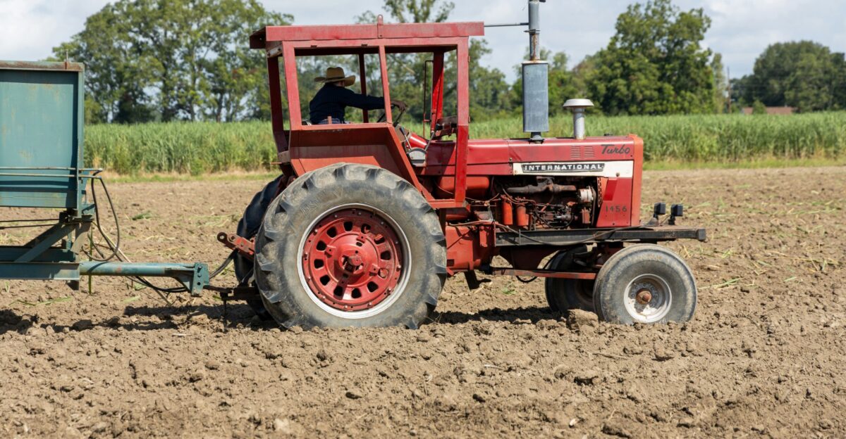 a red tractor and a blue trailer in a field