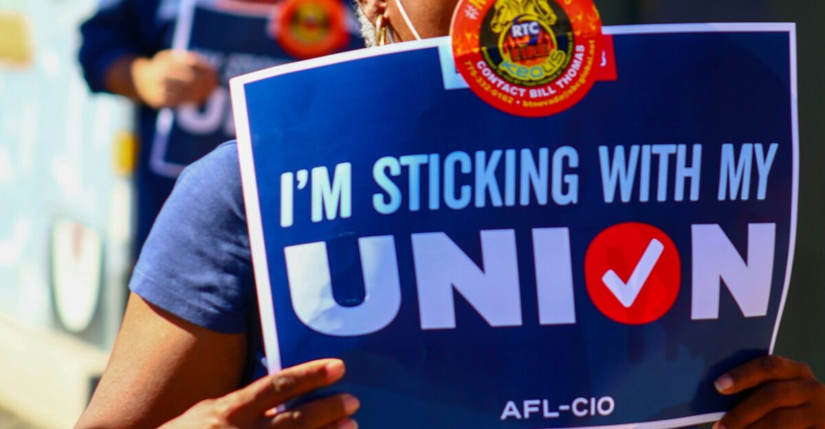 a woman holding a sign that says i'm sticking with my union