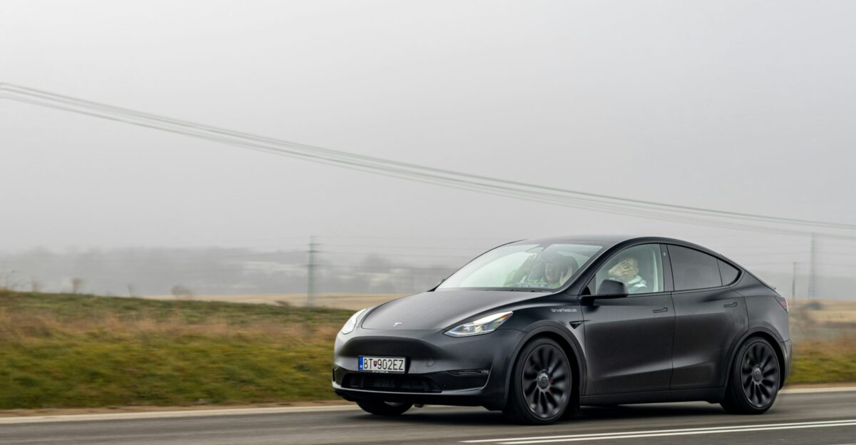 a black tesla car driving down the road