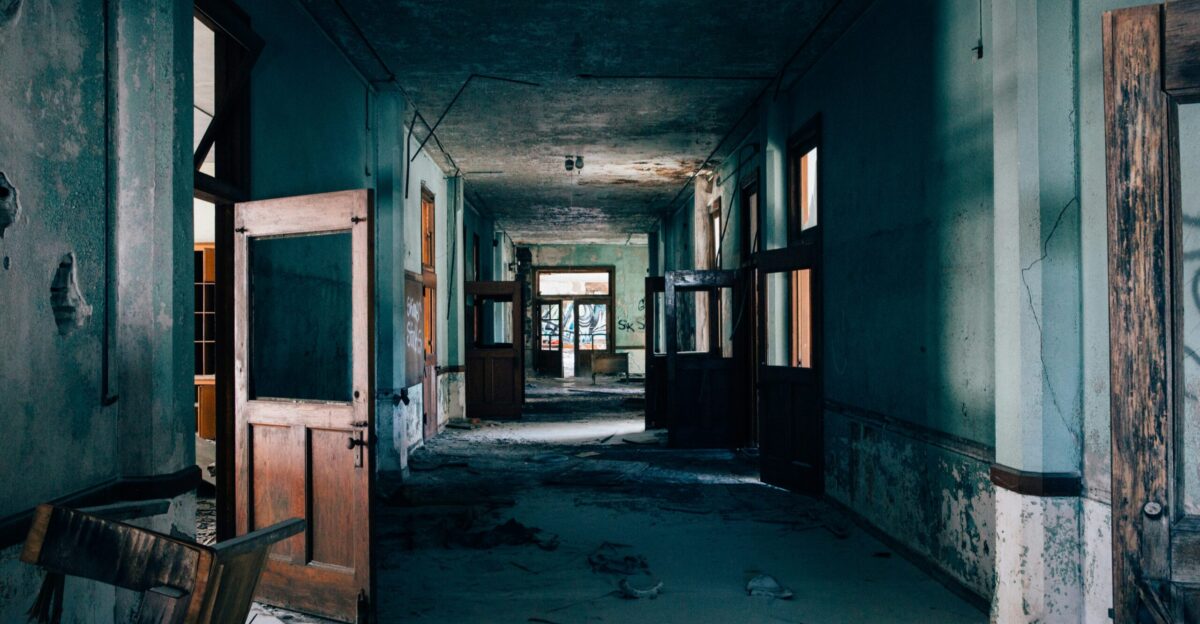 a long hallway in an abandoned building with broken doors