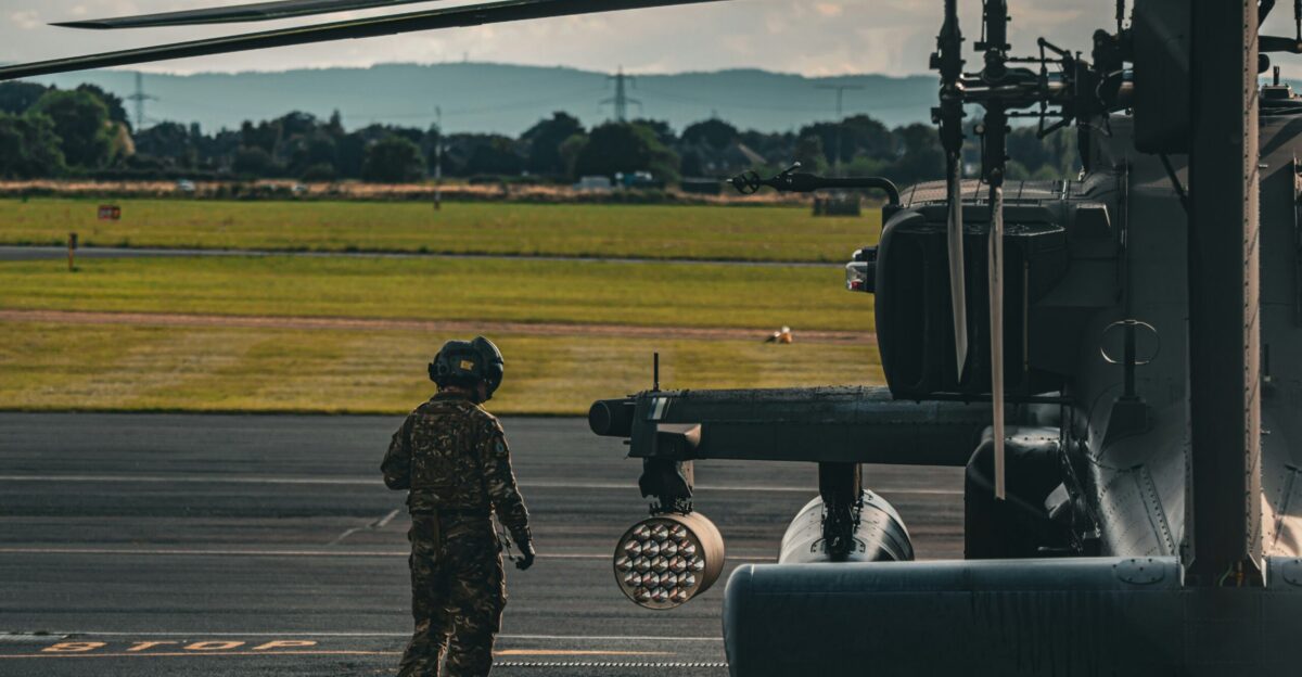 A man standing next to a helicopter on top of an airport tarmac