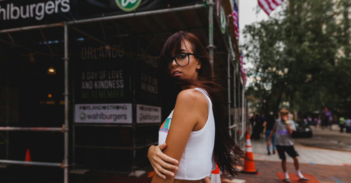 Stylish woman posing in trendy outfit in urban street with American flags
