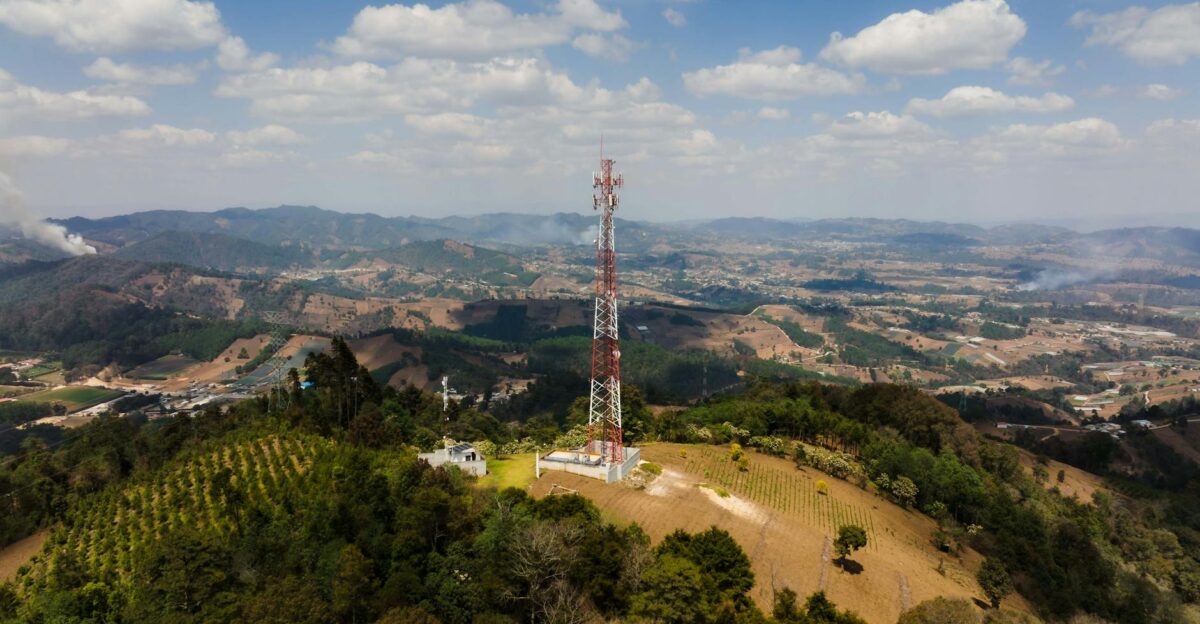 Breathtaking panoramic view of a communication tower on a mountain surrounded by lush landscape and clouds