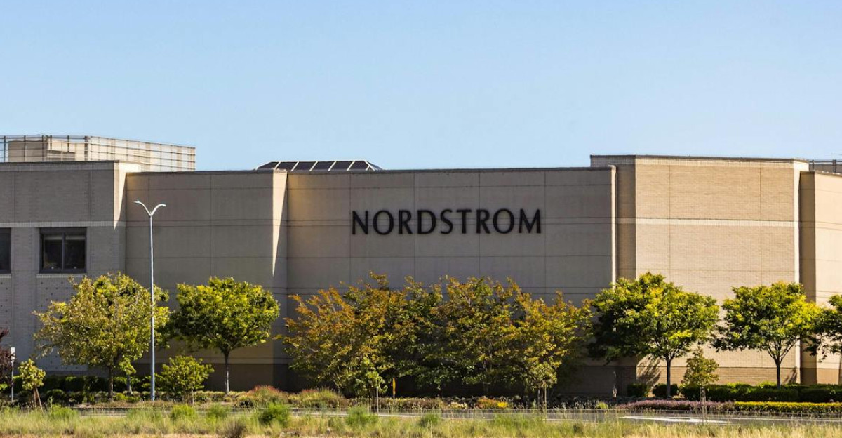 A Nordstrom store building set against a bright clear sky and surrounded by greenery