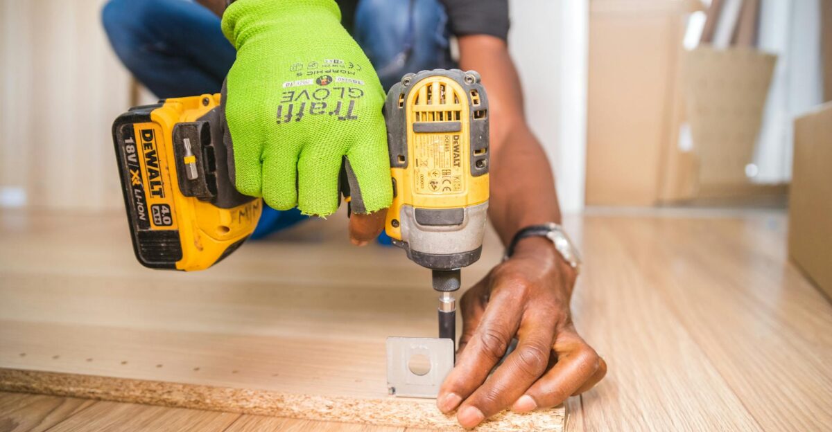 Man using a power drill for home improvement on a wooden floor with precision