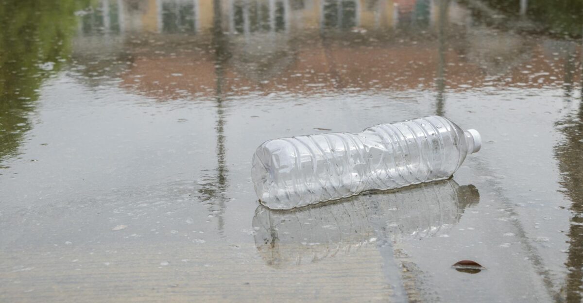 Discarded plastic bottle lying on wet pavement in the rain reflecting environmental issues