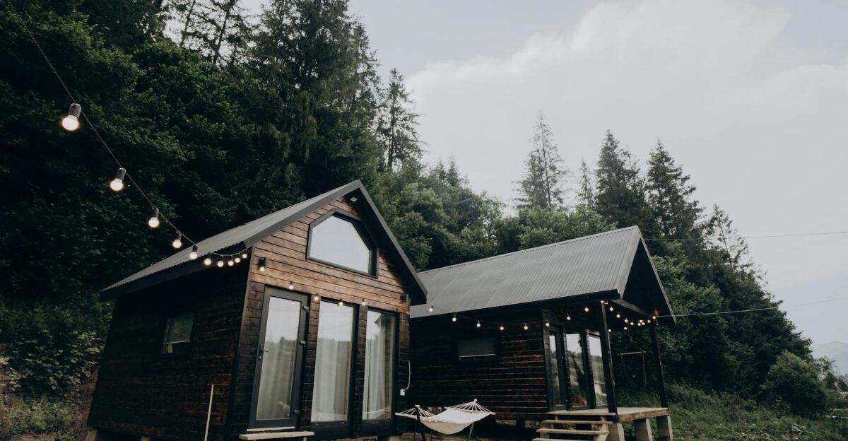 Charming wooden cabins surrounded by lush forest with string lights at dusk creating a serene and cozy atmosphere
