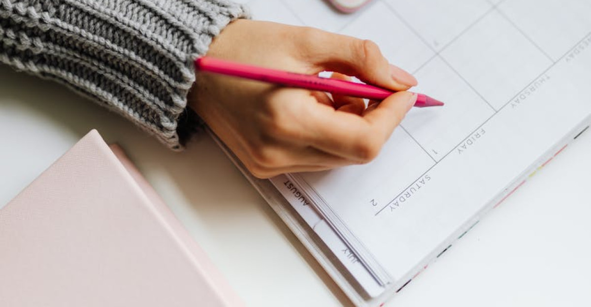 Close-up of a woman planning on a calendar using a smartphone and pen