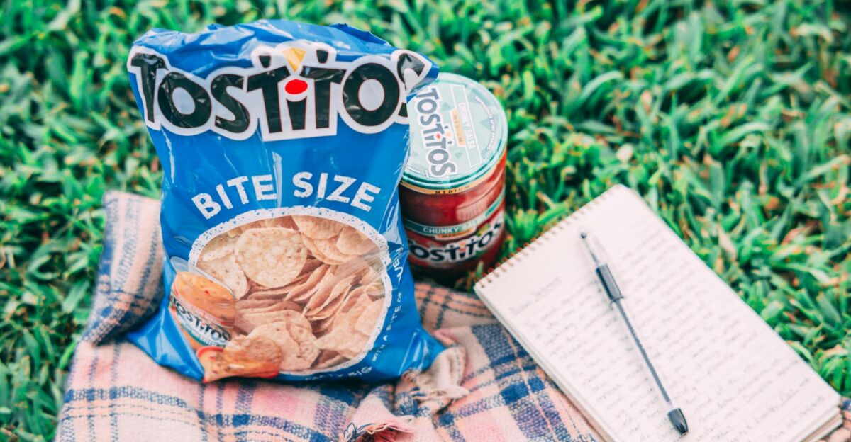 Casual picnic setup with Tostitos chips and salsa on blanket outdoors