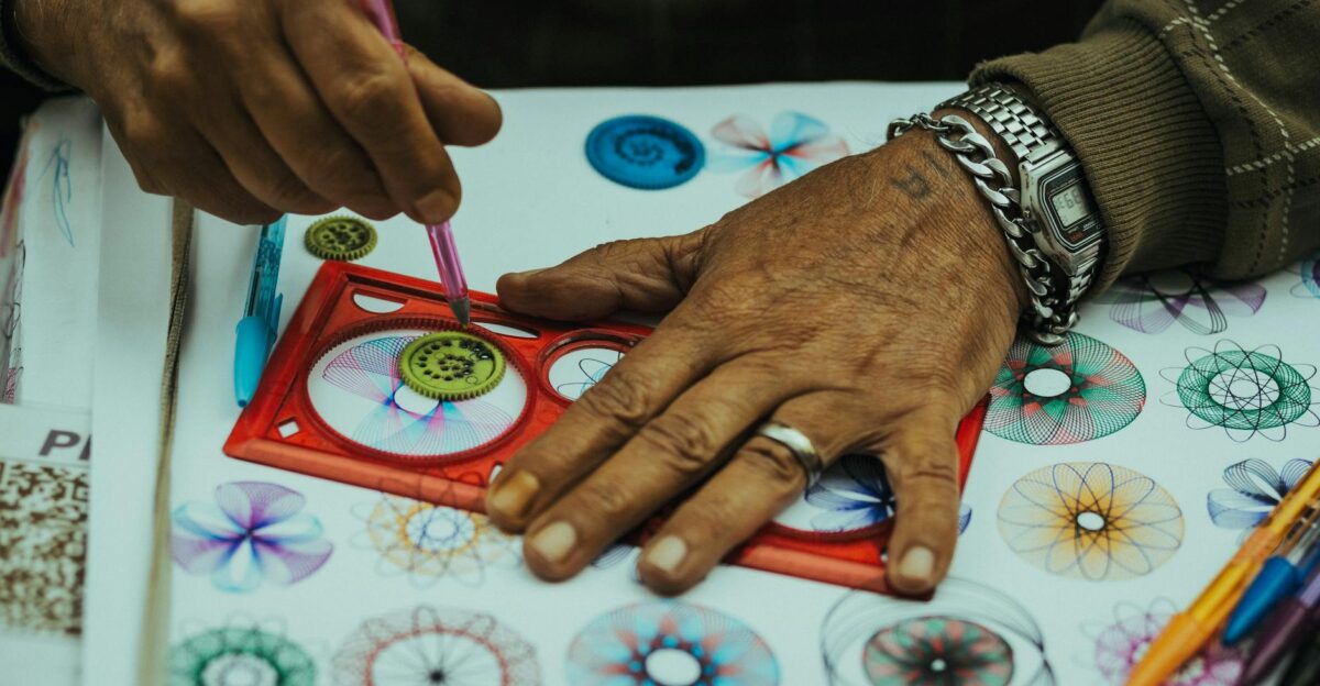 Close-up of hands creating vibrant spirograph patterns with pencils showcasing creativity and precision