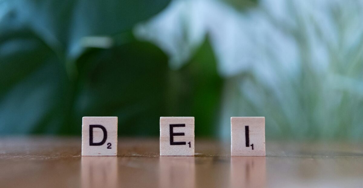 Wooden letter tiles spelling DEI on a table symbolizing diversity equity and inclusion