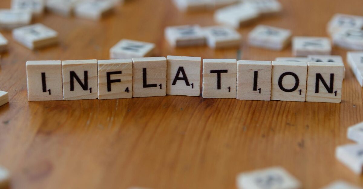 Scrabble letter tiles spelling INFLATION on a wooden table signifying economic concepts