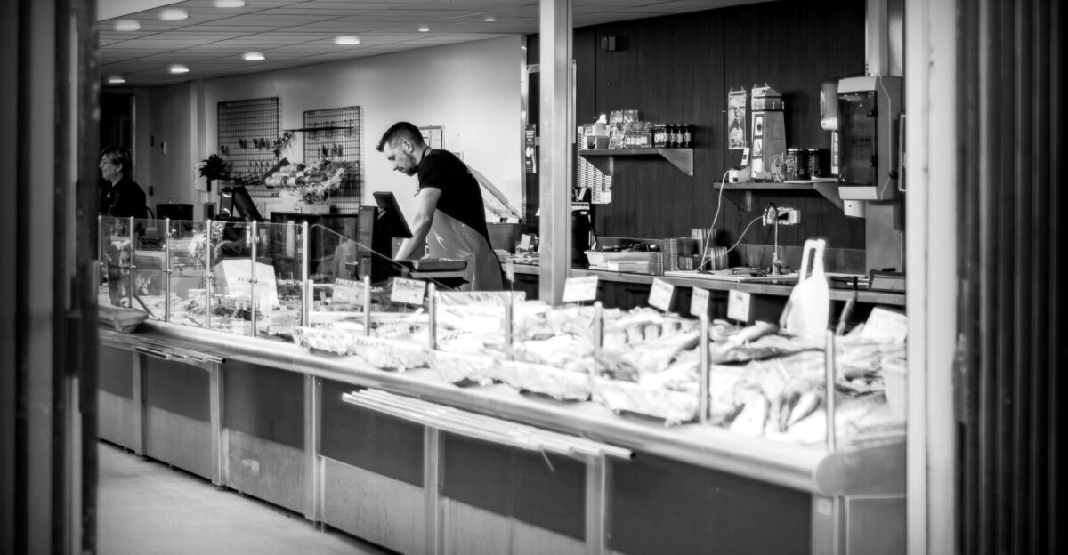 Black and white photo of a fish market with staff in action showcasing fresh seafood