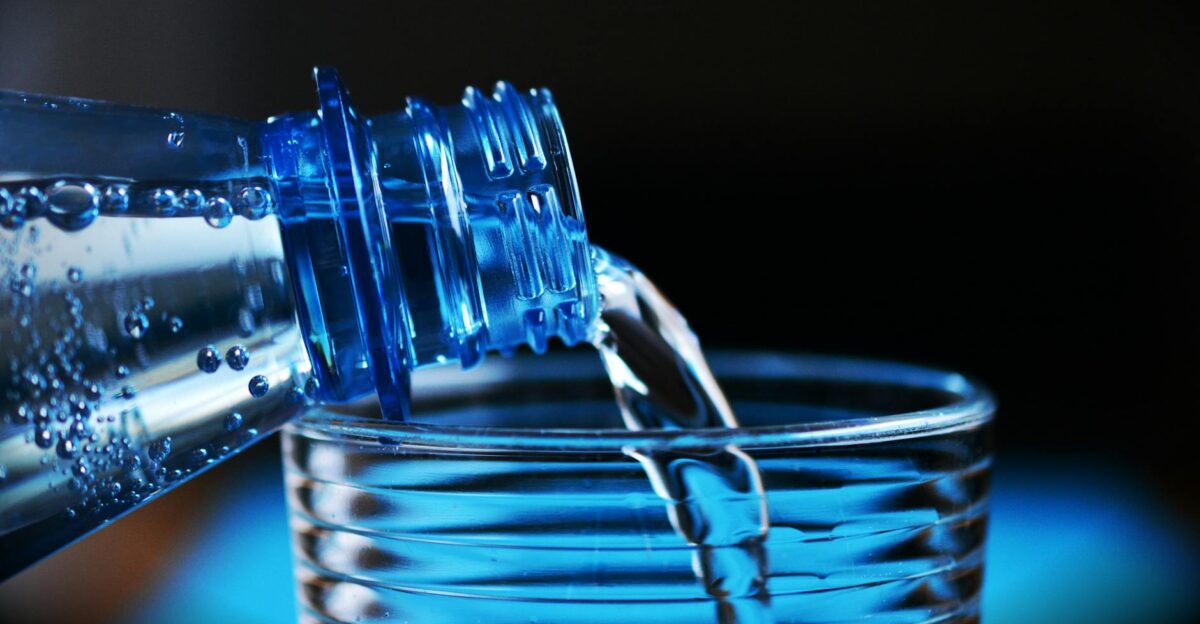 Close-up of sparkling water being poured from a bottle into a glass with bubbles visible