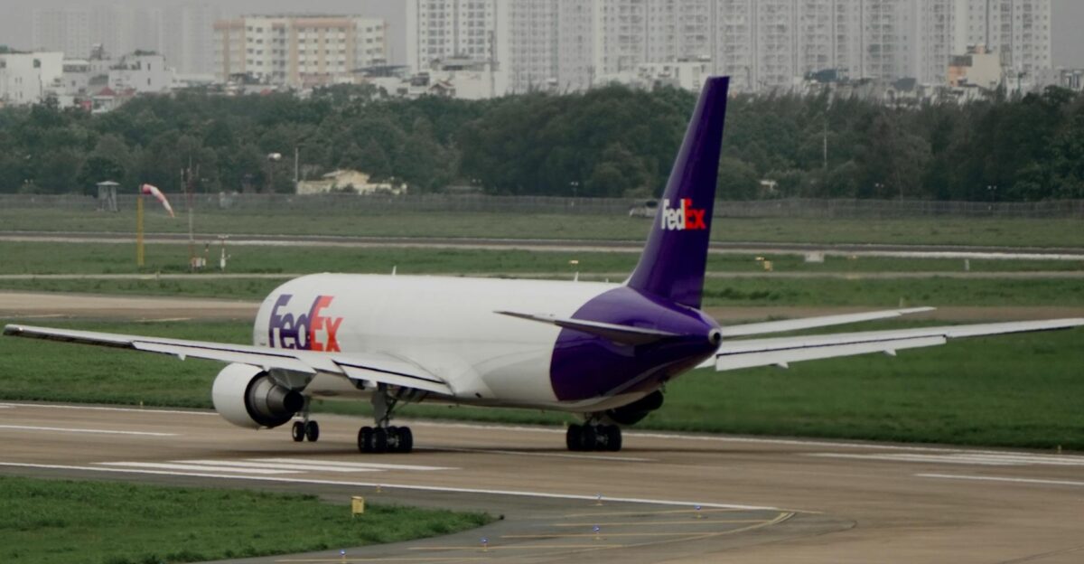FedEx cargo plane on the runway preparing for departure with cityscape in the background