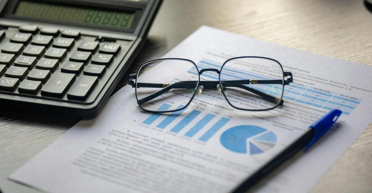 Financial document with a calculator pen and glasses symbolizing data analysis
