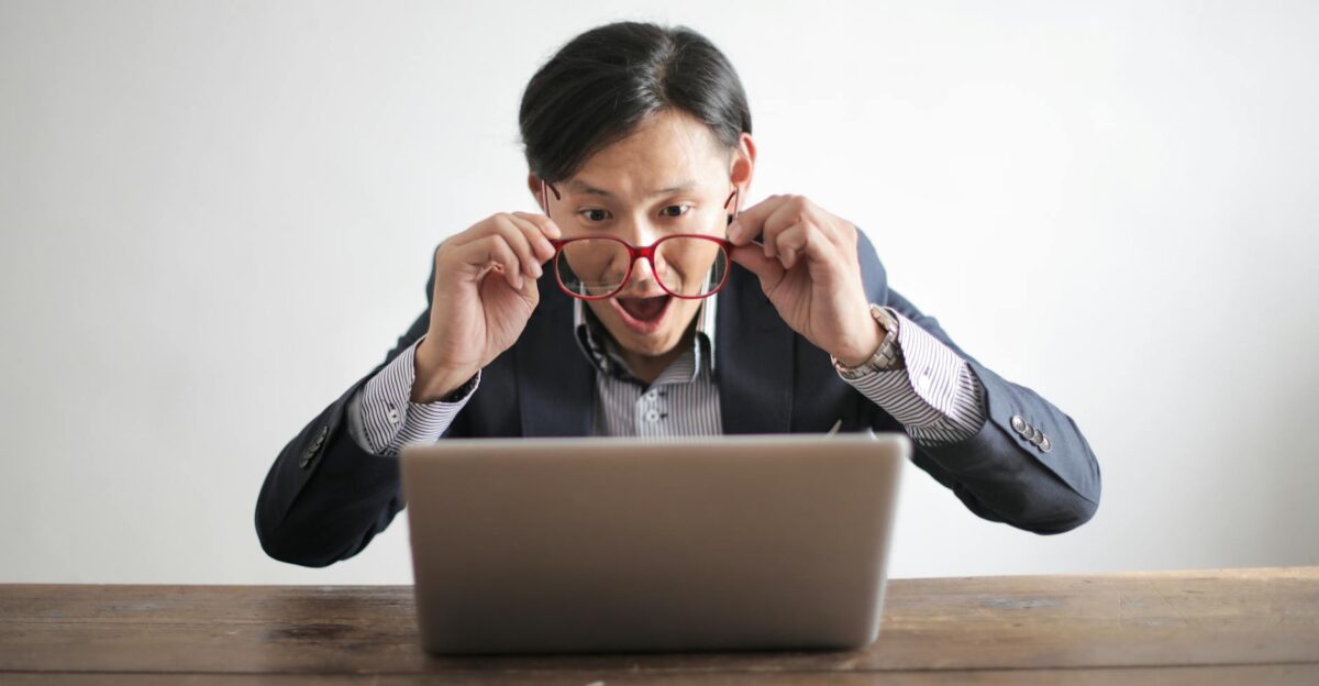 Surprised man in a suit looking at laptop expressing disbelief indoors