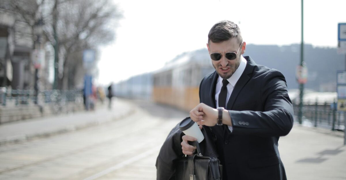 A businessman in a suit checks his watch while rushing on a sunny day in the city