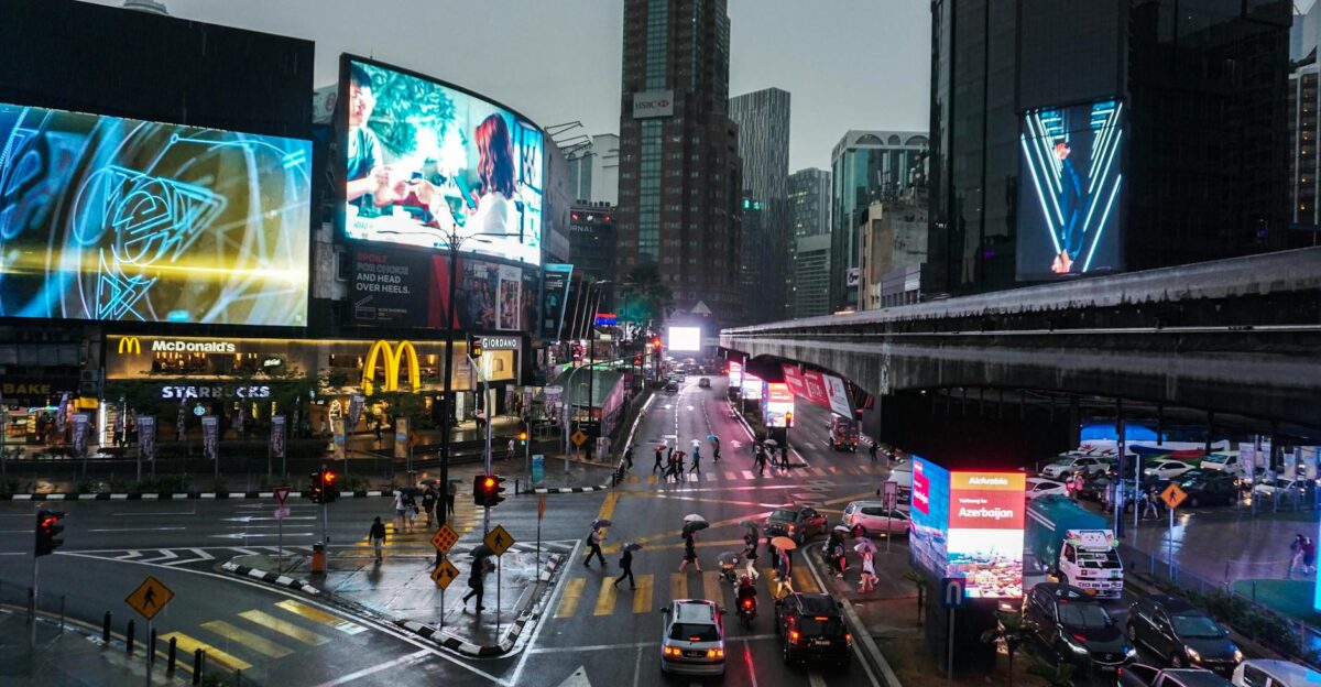 Crowded intersection in Kuala Lumpur at night with vibrant billboards and traffic
