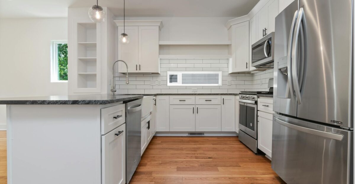 Spacious white kitchen featuring modern appliances and wooden flooring for a stylish look