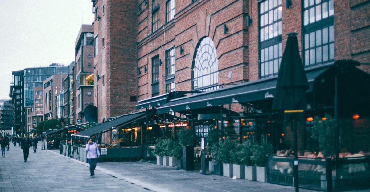 Historic urban street featuring brick buildings and a lively outdoor cafe in twilight