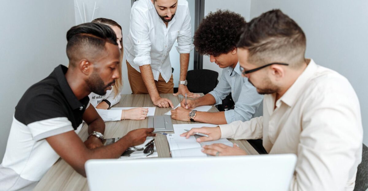 A diverse group of professionals actively collaborating at an office table during a business meeting