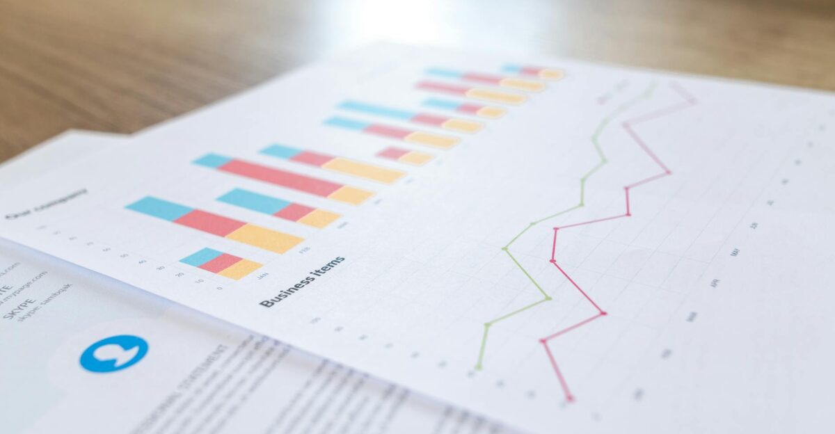 A close-up view of a business document with charts and graphs on a wooden desk