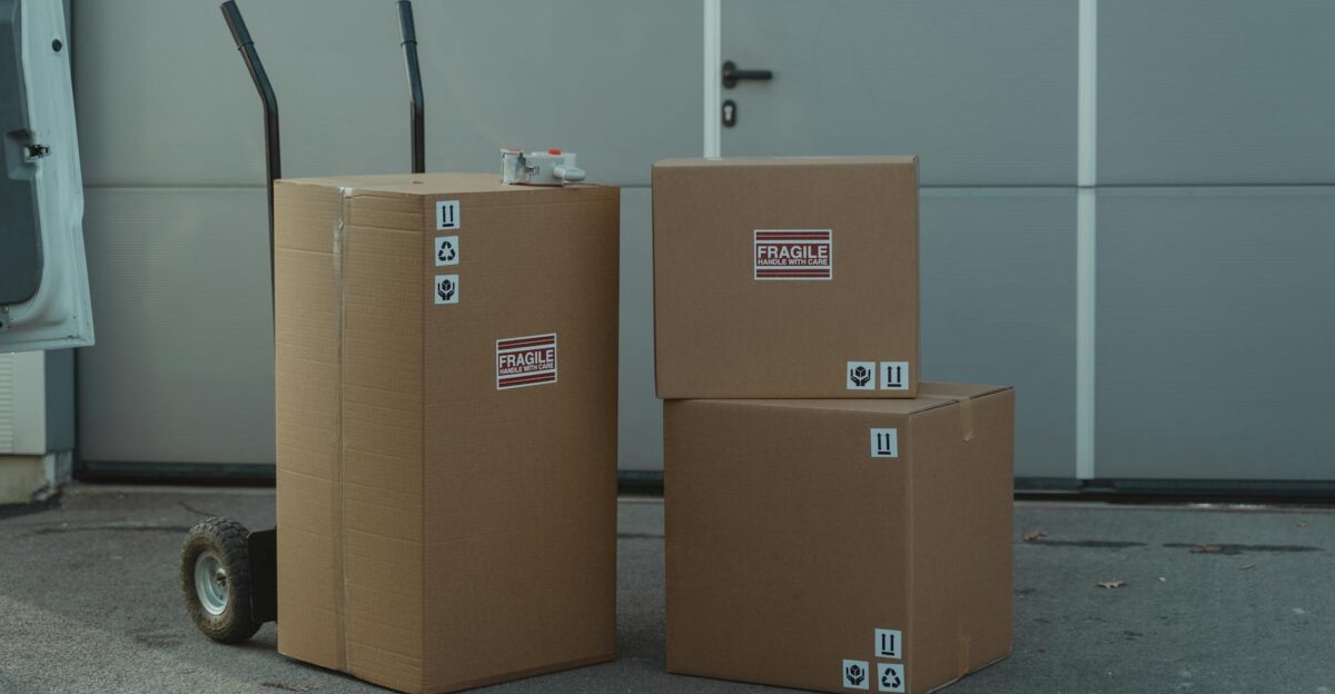 Three cardboard boxes on a dolly ready for shipping outside a warehouse