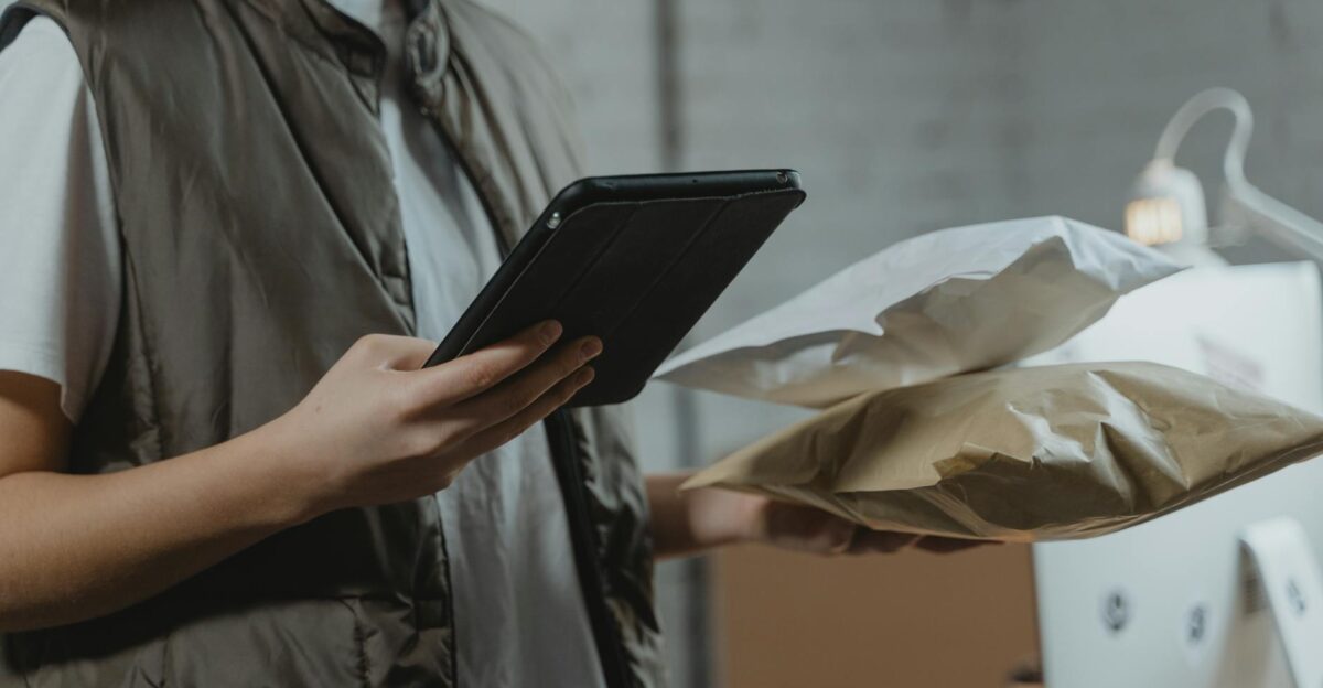 A person using a tablet to manage packages in an indoor setting highlighting technology and logistics