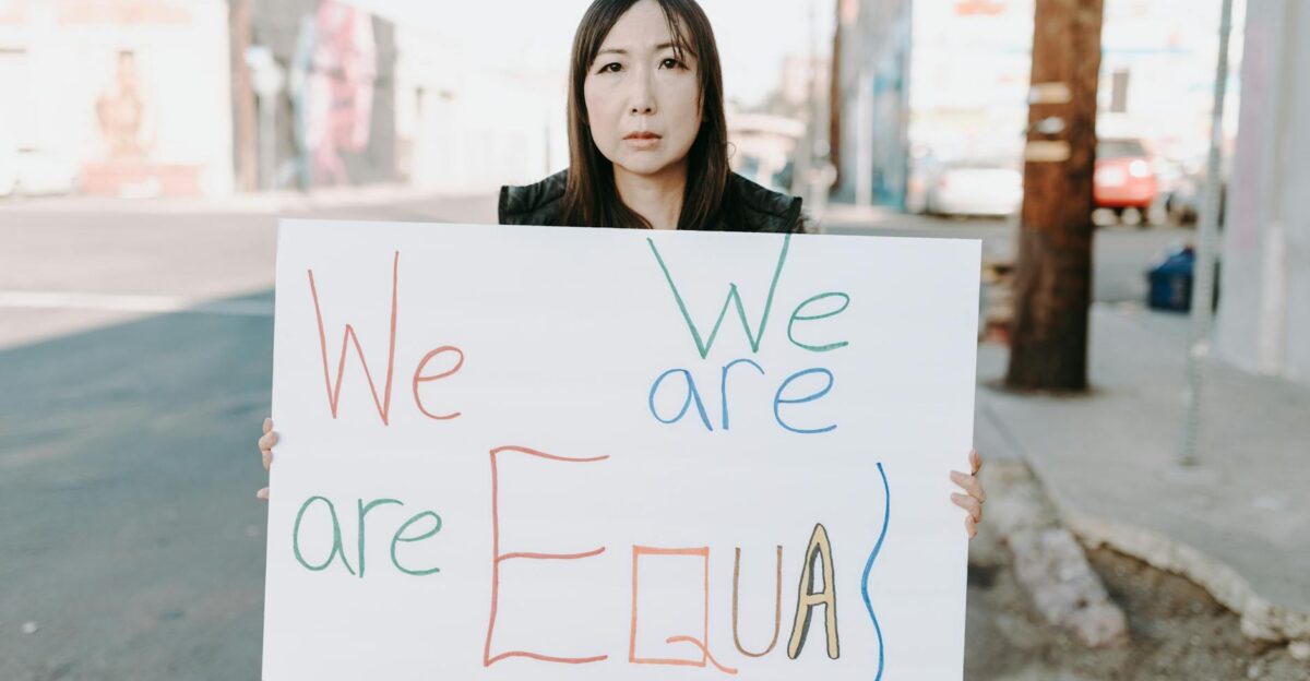 Empowering image of an Asian woman holding a sign promoting equality during a street protest