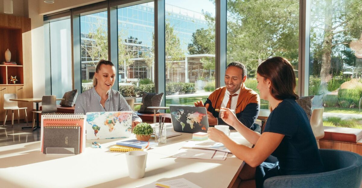 Three colleagues brainstorming with laptops in a well-lit office