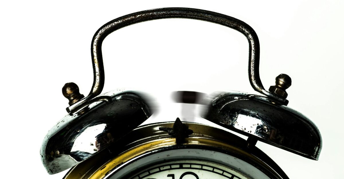 Close-up of a classic vintage alarm clock with ringing bells on a white background