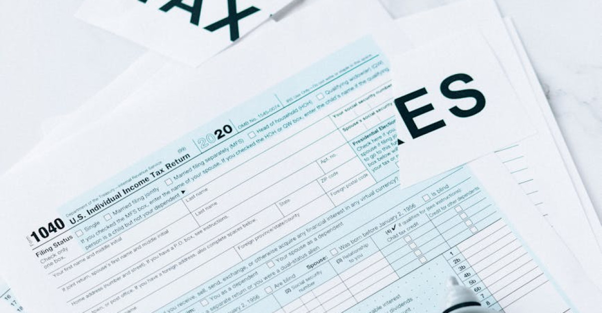A US tax form 1040 with a small clock on a marble surface symbolizing tax deadline urgency