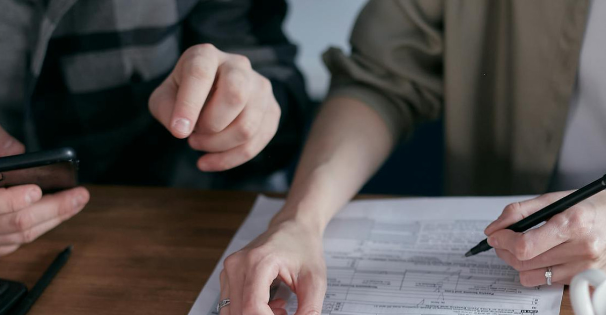 Couple managing finances at home with a calculator smartphone and documents