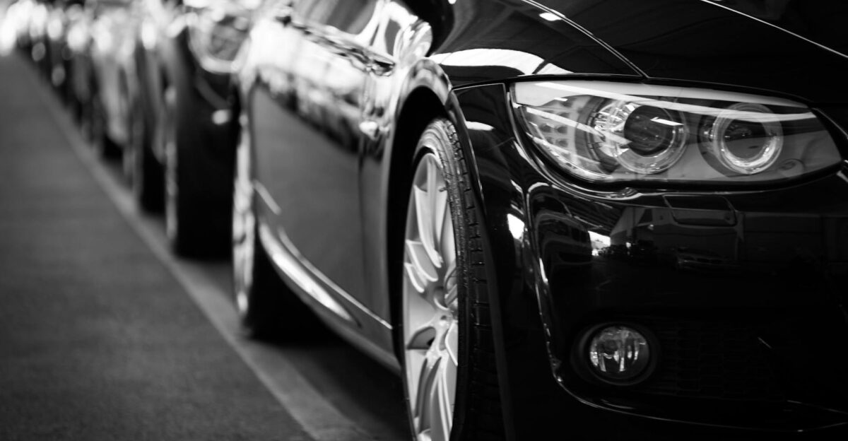 Close-up black and white image of a luxury car line-up focusing on vehicle headlights